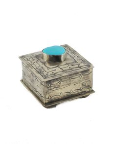 an old silver box with a blue knob on the top and bottom, sitting against a white background