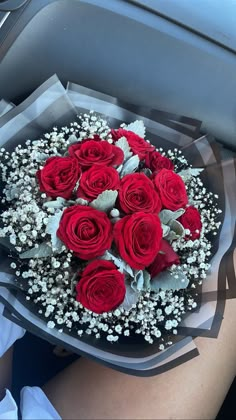 a bouquet of red roses in someone's lap