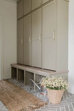 a basket with flowers sitting on the floor next to some cupboards and a rug