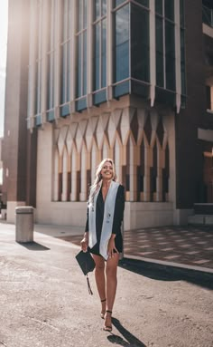 a woman is walking down the street with her hand in her pocket and holding an umbrella