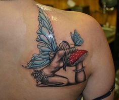 a woman's back with a butterfly tattoo on her left shoulder and the image of a fairy holding a mushroom