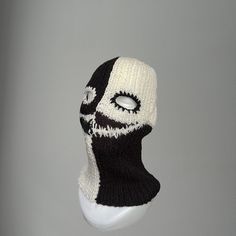 a white and black knitted mask hanging on a wall