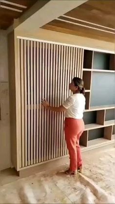 a woman standing in front of a bookshelf with shelves behind her on the floor