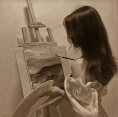 a woman is painting on an easel with a paintbrush in her left hand