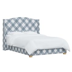 an upholstered bed with white sheets and blue checkered headboard