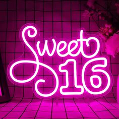 a neon sign that says sweet sixteen in front of a vase with flowers on it