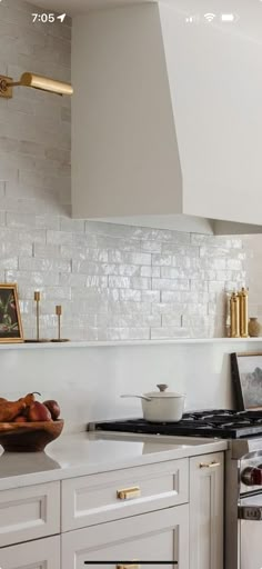 a kitchen with white cabinets and gold trim on the hood, stove top and oven