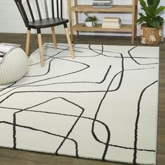 a white rug with black lines on it and a chair next to it in front of a bookshelf