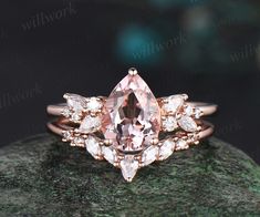 a pink diamond ring sitting on top of a green rock