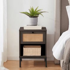 a nightstand with a basket on top and a plant in the corner next to it