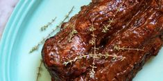 a piece of meat on a blue plate with sprigs of thyerole