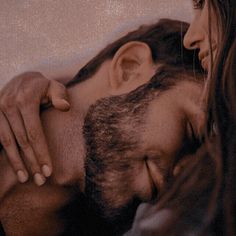 a close up of a person with long hair and a beard holding another persons head