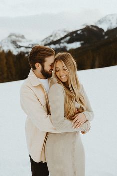 a man and woman hugging in the snow