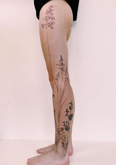 a woman's legs with tattoos on them and flowers growing out of the leg