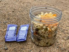 a jar filled with macaroni and cheese sitting next to two bags of pasta