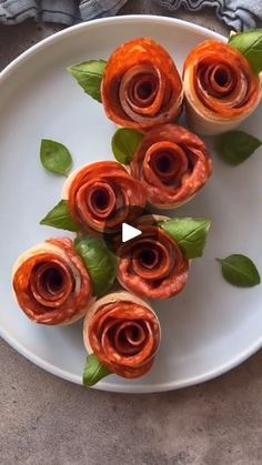 some food is laying on a white plate with green leaves and flowers in the middle