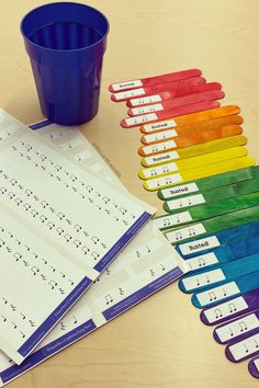 a cup, rulers, and paper on a table with the colors of the rainbow