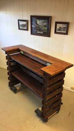 a desk made out of wooden pallets in a room with pictures on the wall