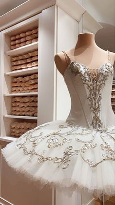 a white ballerina dress sitting on top of a mannequin in front of shelves