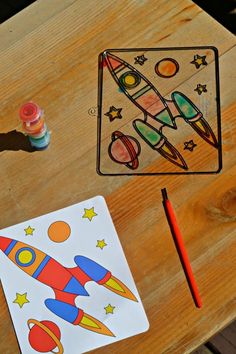 a wooden table topped with crafting supplies and a coloring book on top of it