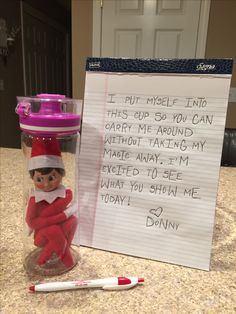 an elf is sitting in a jar next to a note