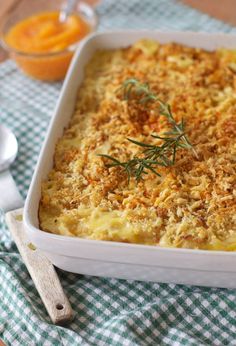 a casserole dish with cheese and herbs in it on a checkered cloth