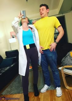 a man and woman standing next to each other in a living room with wood floors