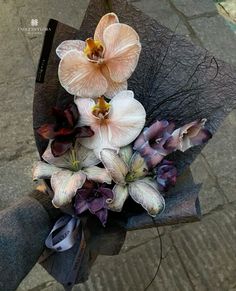 a bouquet of flowers sitting on top of a black piece of paper next to a sidewalk