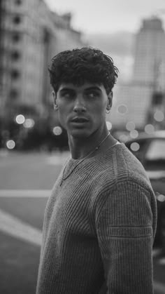 a young man standing in the middle of a street at night with traffic lights behind him