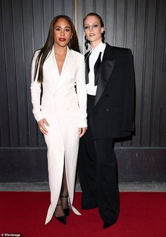 two people standing next to each other on a red carpet