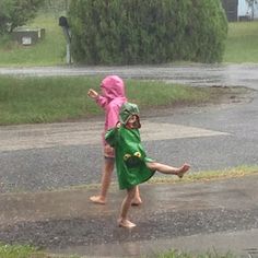 two children in raincoats playing on the street