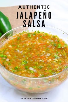 a glass bowl filled with soup next to green peppers and cucumber on the side