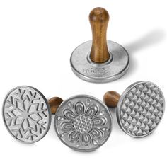 three metal stampers with wooden handles and designs on them