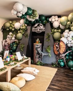 a room filled with balloons and dinosaurs on the wall next to a table full of stuffed animals