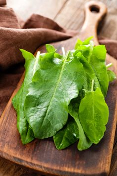 some green leafy vegetables on a wooden cutting board