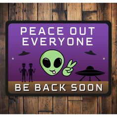 a sign that says peace out everyone be back soon on a wooden background with aliens