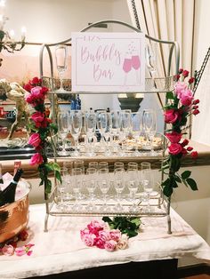 there are many wine glasses on the table with flowers around it and a sign that says bubbles bar