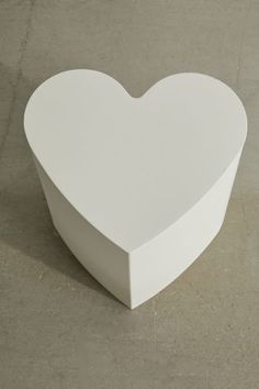 a white heart shaped box sitting on top of a cement floor