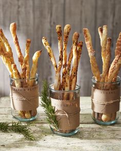 three glass jars filled with food on top of a wooden table