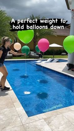 a woman standing next to a swimming pool with balloons floating in the water and an advertisement on it that says, a perfect weight for hold balloons down