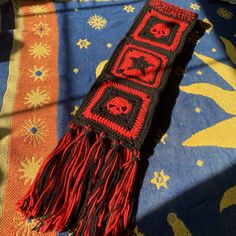 a crocheted scarf with skulls and hearts on it sitting on top of a blanket