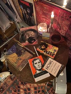 a table topped with books and candles next to a wall covered in posters on it