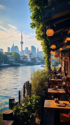 an outdoor restaurant overlooking the water with people sitting at tables