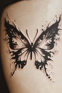 a black and white butterfly tattoo on the back of a woman's stomach,