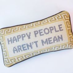 a cross stitch pillow with the words happy people aren't mean written on it