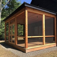 a small wooden structure sitting on top of a grass covered field next to a forest