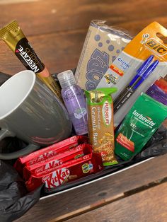 a cup filled with lots of different types of food and snacks on top of a wooden table