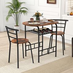 a small table with two chairs and a potted plant in the corner next to it