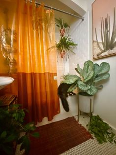 an orange shower curtain in a bathroom next to a potted plant