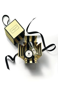 an open box with a black ribbon around it and a small bottle in the middle